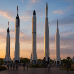 “Rocket Garden no Kennedy Space Center ao amanhecer, com foguetes históricos e céu azul-rosado.”