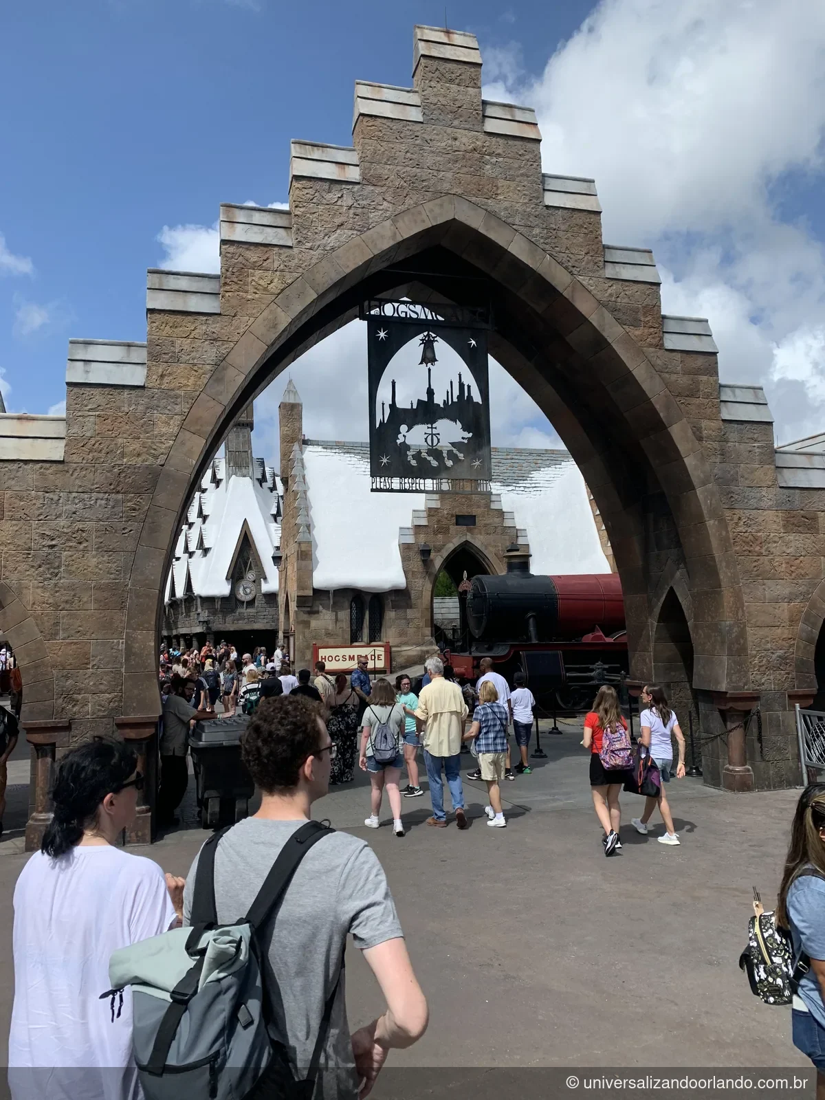 Arco de pedra na entrada de Hogsmeade na Universal, com javalis alados no topo