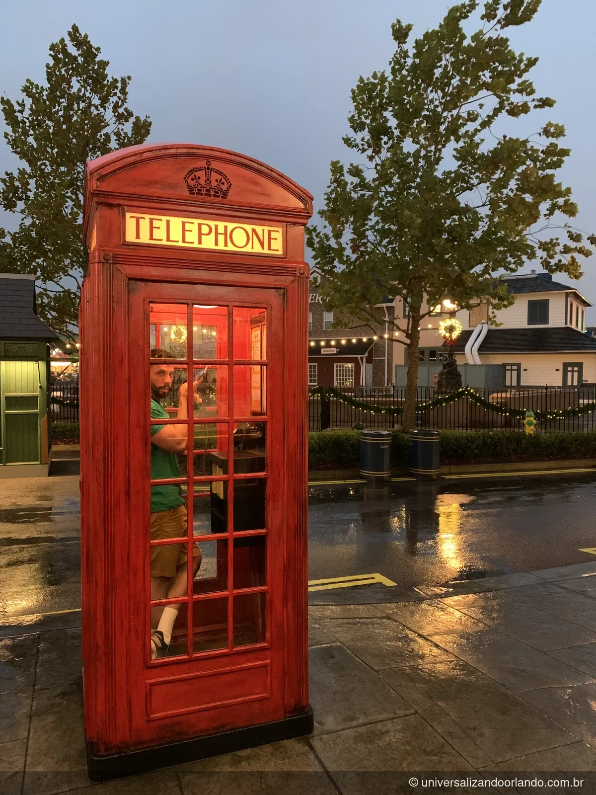 Cabine telefônica vermelha numa rua molhada depois da chuva