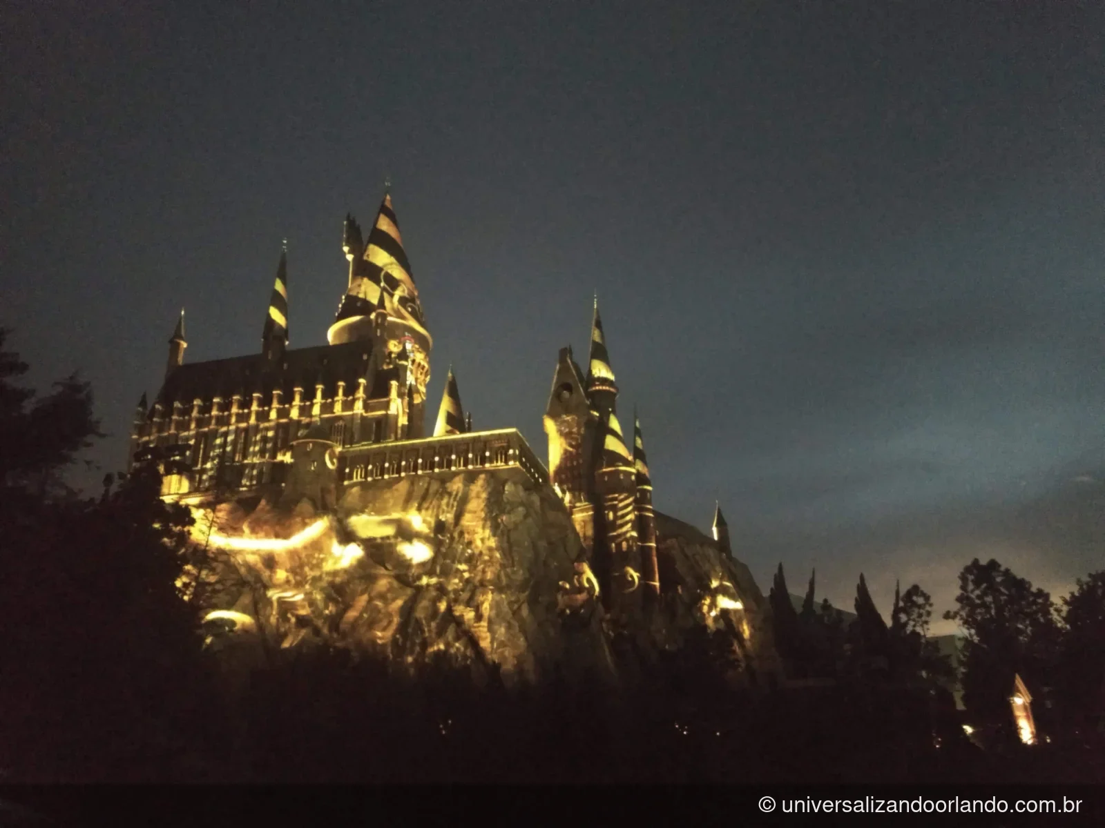 Projeção colorida sobre a fachada do castelo de Hogwarts à noite