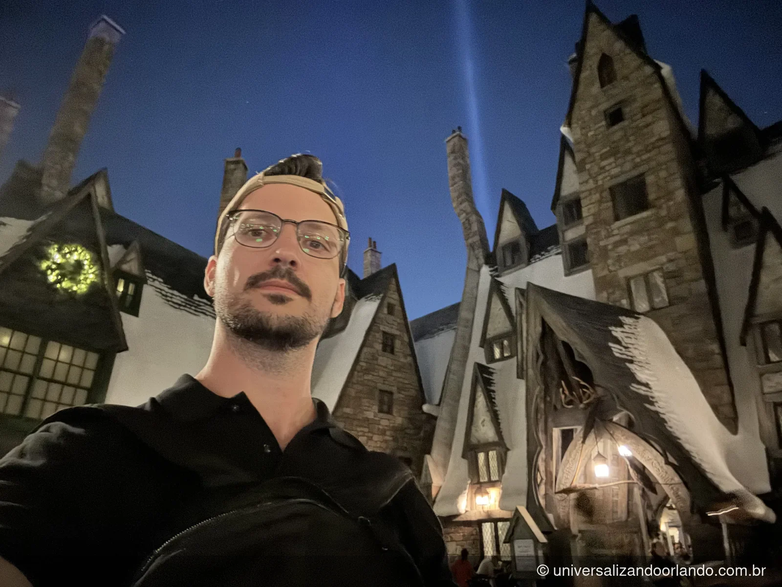 Hogsmeade ao anoitecer, com guirlanda acesa no Natal no mundo bruxo