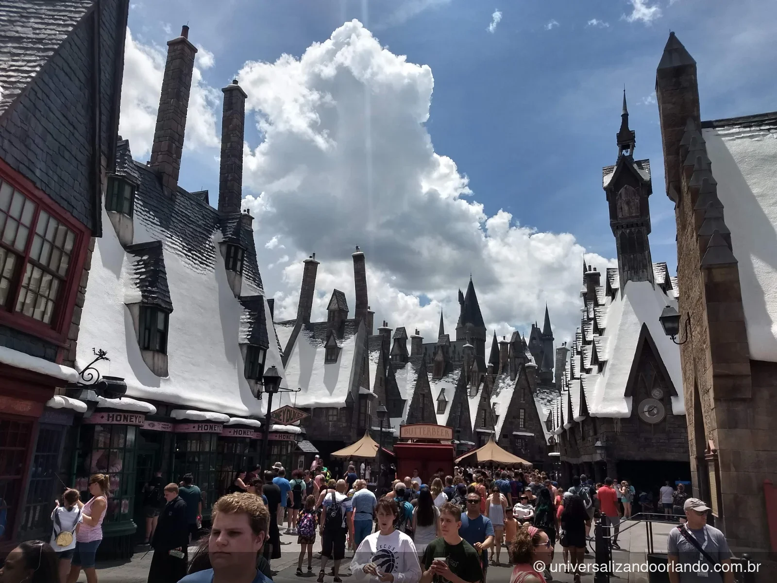 Carrinho de cerveja amanteigada na rua de Hogsmeade, com o castelo ao fundo