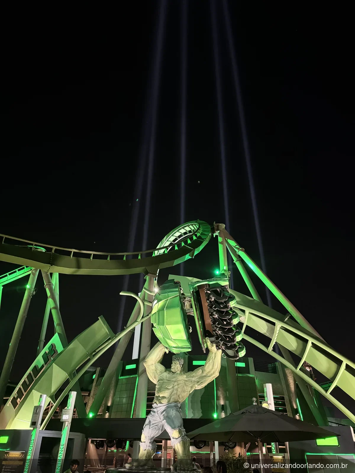 Montanha-russa do Hulk iluminada por holofotes nos parques à noite