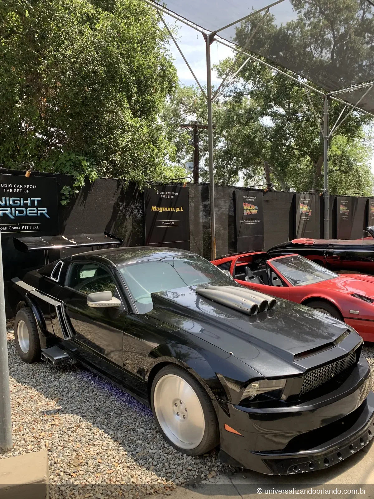 Carros originais de cinema expostos com a placa do filme de cada um