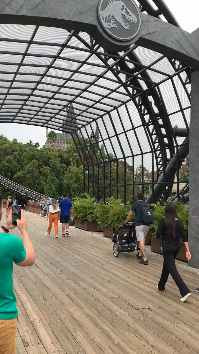 Estrutura de portões de Jurassic World com os trilhos da montanha-russa ao fundo